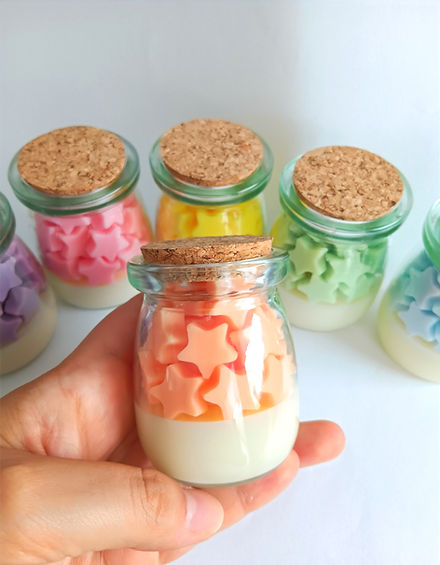 Velas decorativas en envase de vidrio con figuritas en forma de estrella
