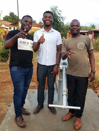 RTH Malawi Staff Alfred, Joshua, and McDonnex smiling in front of newly installed water well.
