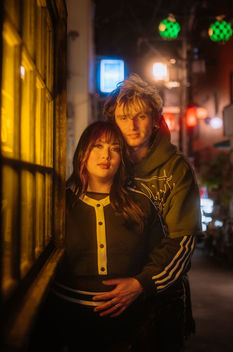 Couple wrapped in a glowing neon warm light in the streets of Nakano Tokyo holding each other romantically