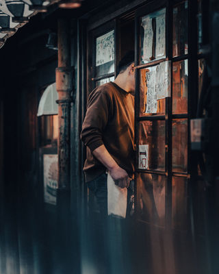  A man looks through the window of a Tokyo restaurant, giving a glimpse into the warm and inviting interior. The scene is set in the quiet hours of the evening, with soft lighting enhancing the atmosphere. NFT Photography by Tokyo Photographer Deniz Demir. Tokyo, Japan.