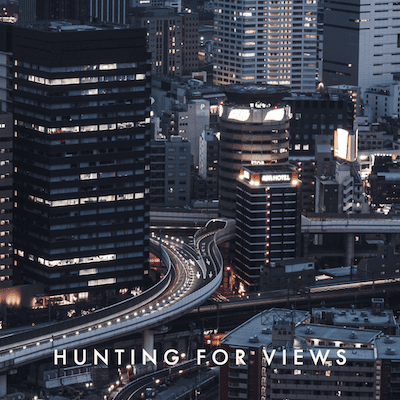 A cityscape with winding highways and skyscrapers, featuring "HUNTING FOR VIEWS" text.