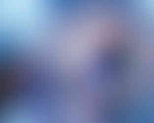 The model lays gracefully on the floor, her sparkling dress shimmering against the reflective surface under blue lighting.