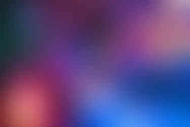 A richly colored scene featuring a woman surrounded by an abundance of pink, purple, and blue flowers. A projection of oversized petals in the background enhances the surreal, painterly lighting cast on her face and dress.