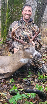 Hunter holding a buck’s antlers in the woods