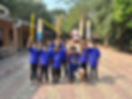 Young cricket team celebrating with trophy and bats