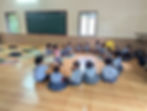 Students in uniforms sitting in a circle in a classroom.