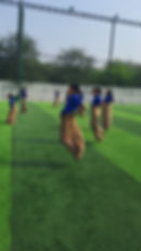 Students participating in a sack race on a green field.