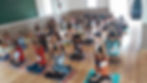 Children sitting on mats practicing yoga in a classroom