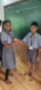 Girl tying a Rakhi on a boy's wrist in a classroom
