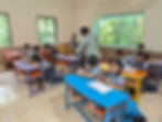 Students in uniforms working at colorful desks in a classroom