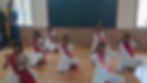 Students performing a traditional dance in a classroom.