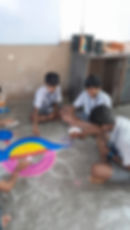 Students creating colorful rangoli art on floor