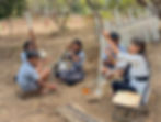 Students and a teacher painting a fence in an outdoor gallery garden.