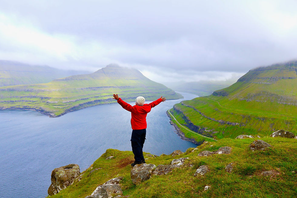 Eye-level view of a traveler standing on a mountain peak overlooking a valley