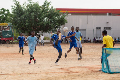 Futbol players competing on a dirt field near the Caxito Province. 