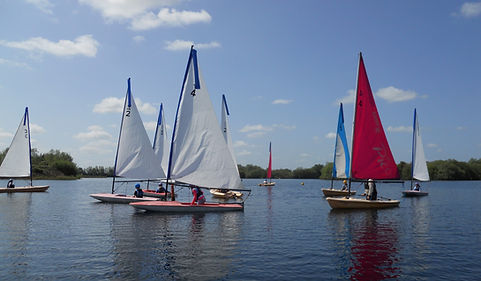 a selection of single handes sailboats taking part in an RYA dinghy course @Girton Sailing Club
