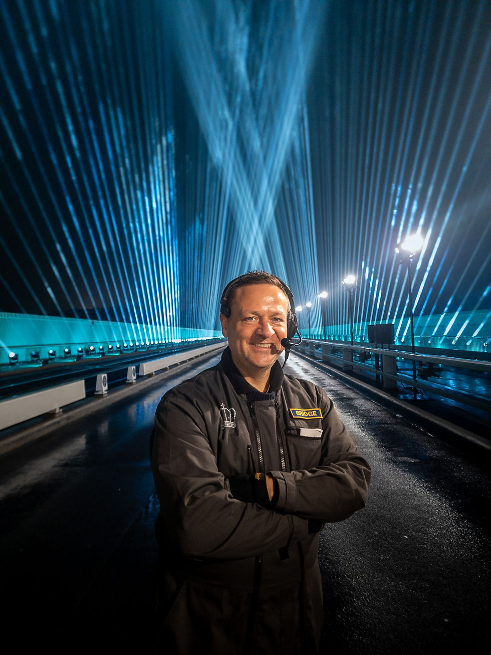 Radja Gios zaakvoerder van Hands 4 Events staat geposeerd met lichtshow als achtergrond