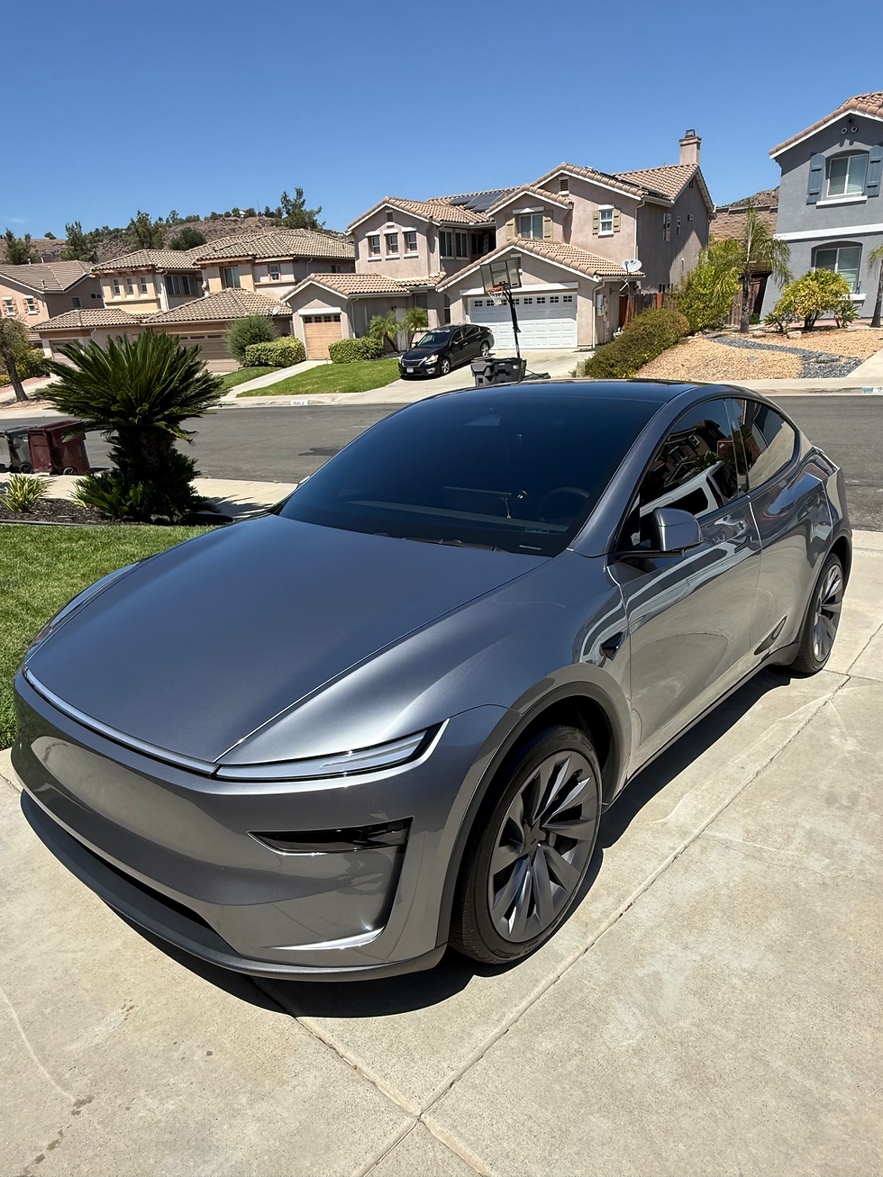 Gray Tesla SUV parked in driveway, showcasing its clean exterior after mobile auto detailing.
