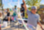 Child creating giant bubbles at a Doodle & Pop interactive bubble station during an outdoor family event.