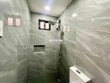 Bathroom with gray marble-style tiles, glass shower enclosure, and toilet.