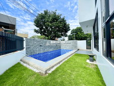 Private backyard with swimming pool, tiled wall, and green lawn, perfect for outdoor relaxation