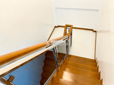 Wooden staircase with stainless steel handrails leading to the second floor.