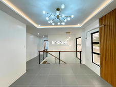 Open hallway and family area with glass railing and modern lighting.