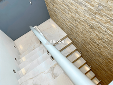 Staircase with stone accent wall and glass railing