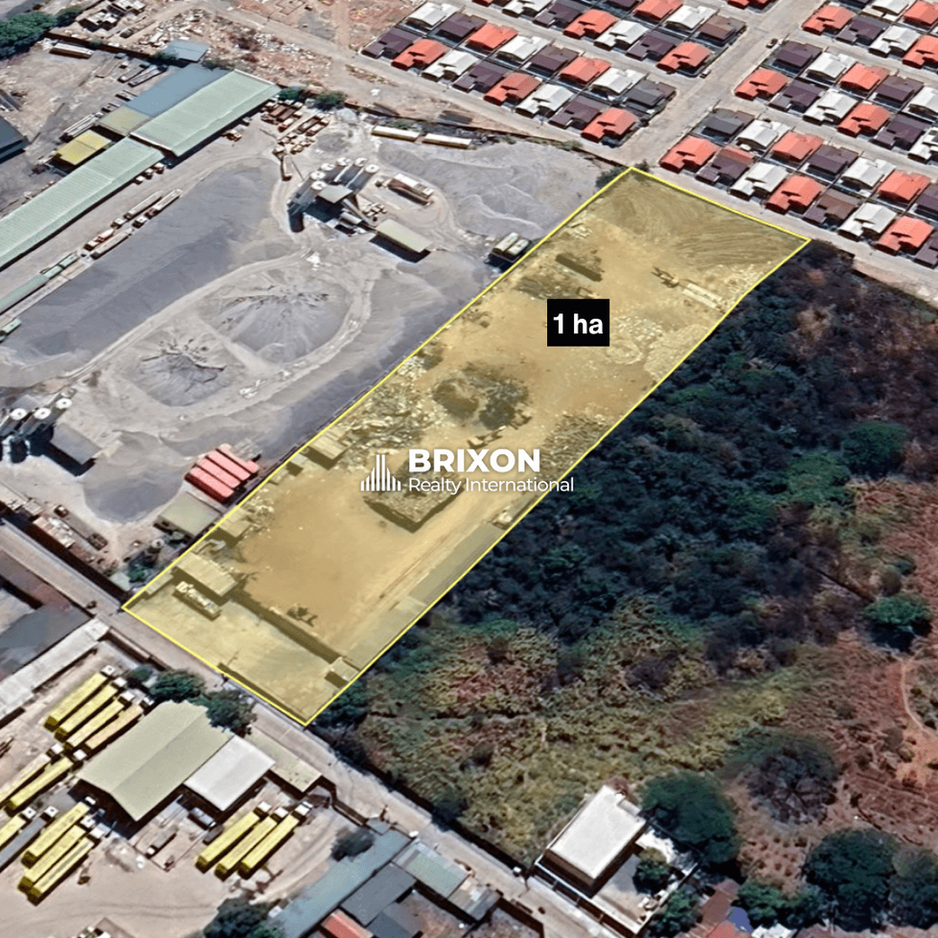 Aerial view of a 1-hectare industrial lot highlighted in yellow, located between an active factory compound and a residential subdivision in Pampanga, labeled “1 ha” with the Brixon Realty International watermark.