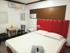 Spacious condotel room with red upholstered headboard, queen bed, and modern furnishings for sale in Angeles City