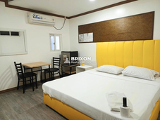 Fully furnished condotel room with yellow headboard, bed, side tables, and guest seating in Balibago, Angeles City