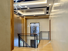 Second-floor hallway with sleek wooden floors, a black metal railing, and a minimalist ceiling light.