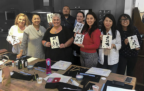 A happy group of people at a japanese calligraphy workshop