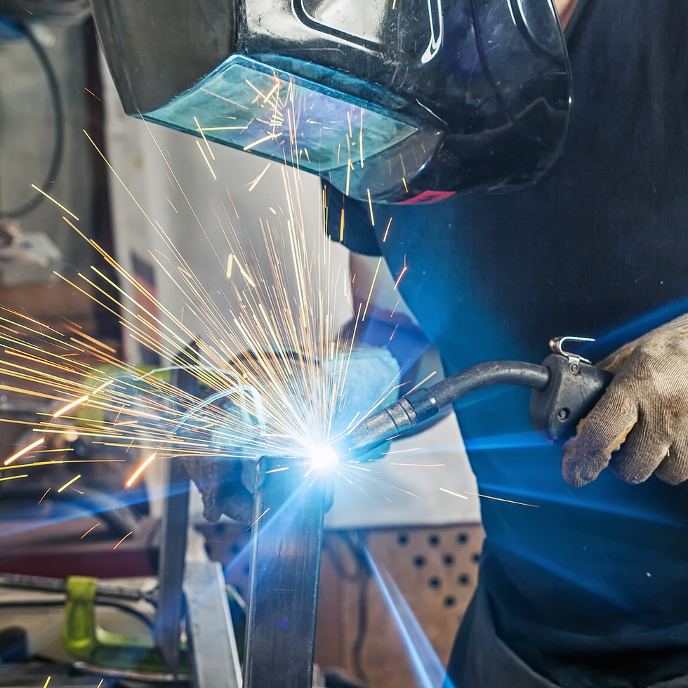 Welder using a MIG welding torch with protective helmet, producing sparks during hands-on training at OWETEC’s Ohio facility.