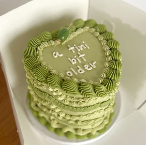 Green heart-shaped vegan birthday cake with “a tini bit older” piping – custom cake by Ventura bakery