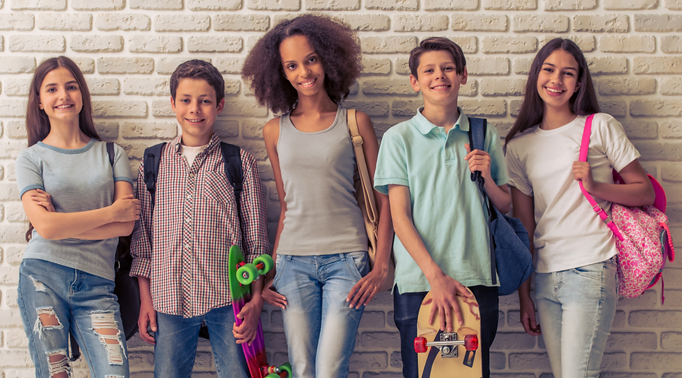 Five middle-aged kids are posing for a photo, standing against a wall.
