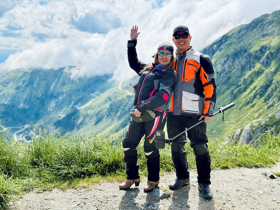 motorcycle rider couple at Furka Pass with selfistick camera, grimsel pass in the background, guided motorcycle tour with motovibes travel
