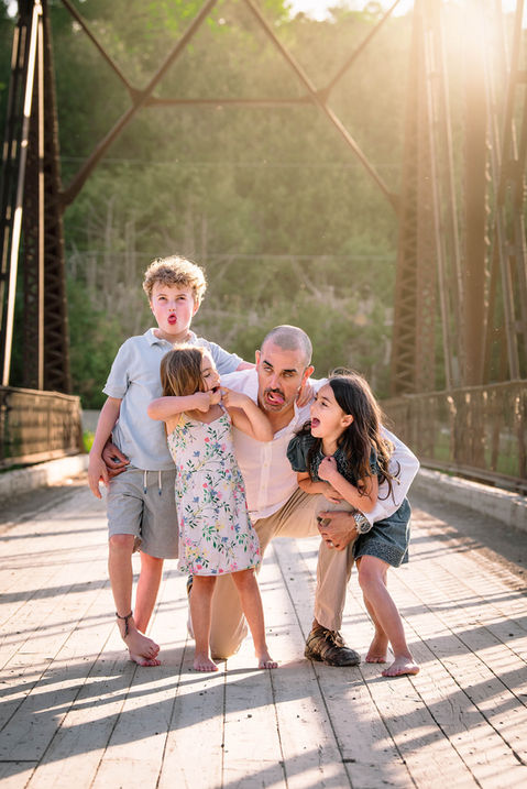 A father and his three young kids making funny faces during a family photo session