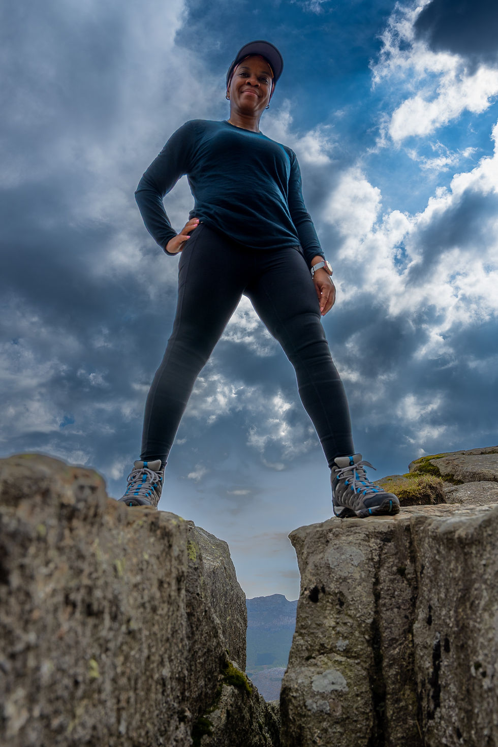 Hiker standing between two rocks on Pulpit Rock (Preikestolen) under dramatic sky during a private guided hike in Stavanger, Norway