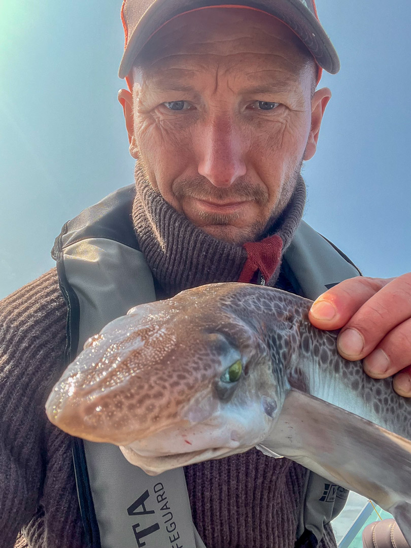 Guide holding freshly caught fjord fish during a private fjord fishing tour near Stavanger, Norway
