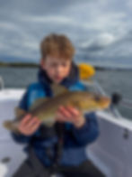 A young angler proudly holding a cod caught during a private fishing trip in the calm Stavanger fjords