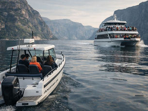 Private fjord tour boat passing a large shared sightseeing boat in a Norwegian fjord