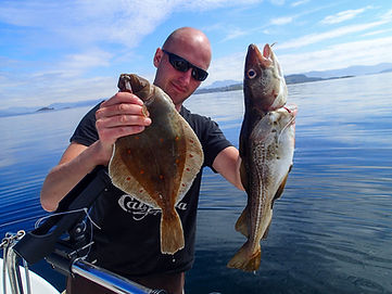 Guide holding plaice and cod during a calm fjord fishing trip in Stavanger, Norway