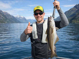 Private fjord fishing tour in Stavanger with guest holding cod in calm fjord surroundings