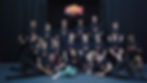 Group of teens and instructors posing in black ACTION! Stunt Boot Camp shirts on a stage, smiling under a logo backdrop.