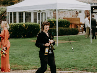 Jess (Wedding Coordinator) setting out table wine during a wedding reception at The Orangery Suite in Wimborne