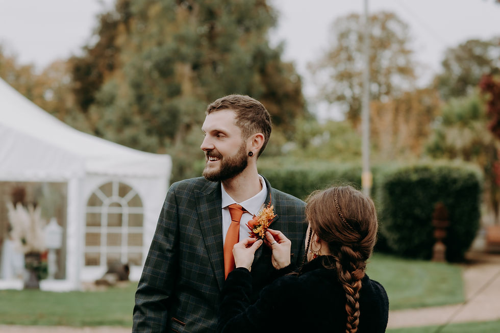 Wedding coordinator putting on a groom's buttonhole. Orangery suite in Wimborne, Poole, Dorset