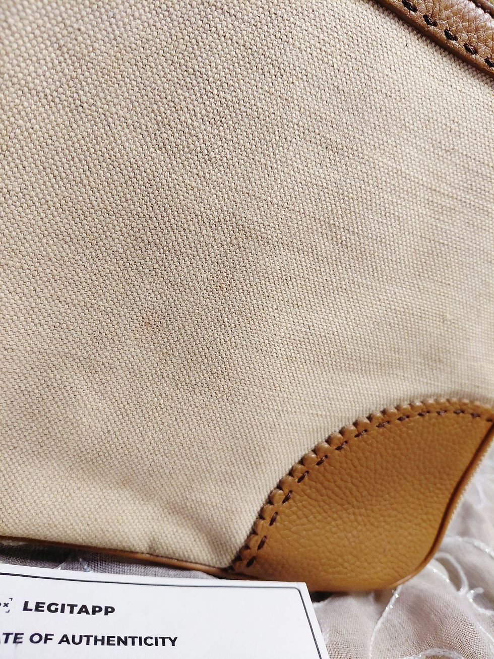 Thumbnail: Close-up of cream Prada canvas showing very light scattered age-related speckling near leather corner trim.