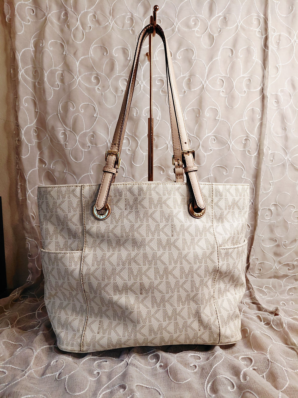Back view of Michael Kors vanilla signature tote showing exterior slip pockets and adjustable shoulder straps.