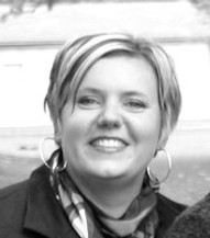 A black and white photo of Elaine Wiersma. A white woman with short hair with a neck scarf and loop pendants.